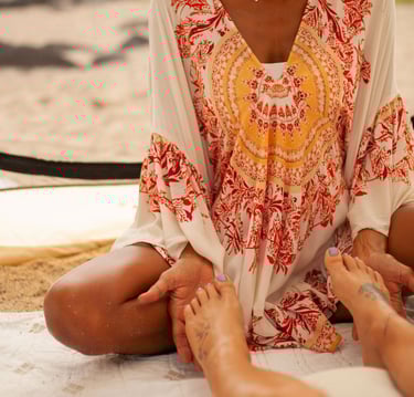 a woman sitting on a blanket doing reiki on a patient's feet