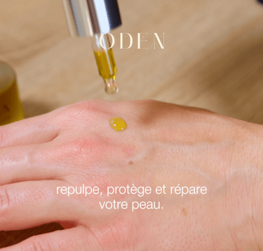 a person's hand holding a bottle of oil cosmetic