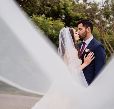 a bride and groom kissing in a veiled veil