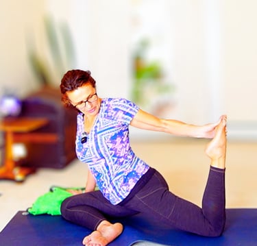 Woman practicing the King Pigeon yoga pose on a blue mat for flexibility and core strength.