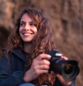 a woman sitting on a rock with a camera