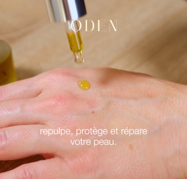 a person's hand holding a bottle of oil cosmetic