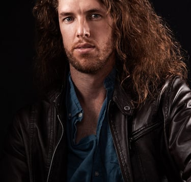 a man with long hair and a beard wearing a leather jacket