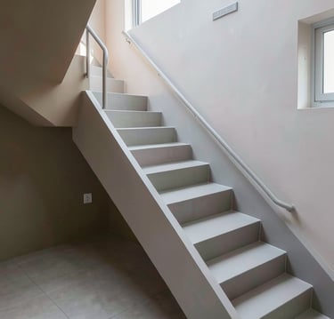 Modern minimalist white indoor staircase with metal handrails and neutral plaster walls.