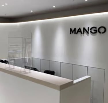 Minimalist Mango retail store interior featuring a white checkout counter and brand logo.
