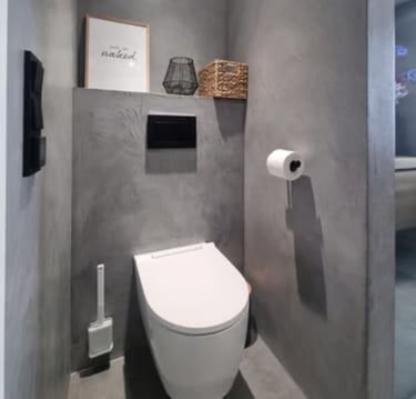 Modern bathroom interior featuring a white wall-hung toilet against grey microcement walls.