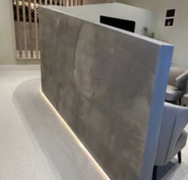 Modern waiting area with grey textured microcement partition with under-cabinet lighting and leather