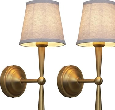 Pair of antique brass gold wall sconce lamps with light beige fabric shades.