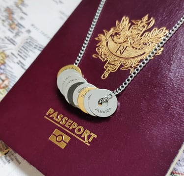 Silver necklace with engraved country tokens resting on a burgundy French passport and world map.