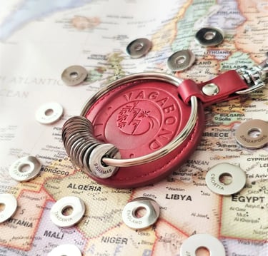 Red leather Vagabond travel keychain with engraved country rings on a world map.