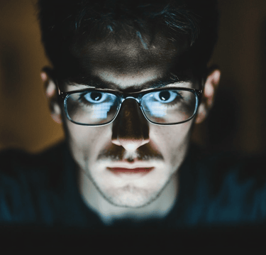 a man in glasses and glasses looking at a laptop