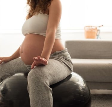 a pregnant woman sitting on a ball with her belly
