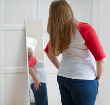 a woman in jeans and a red shirt is standing in front of a mirror