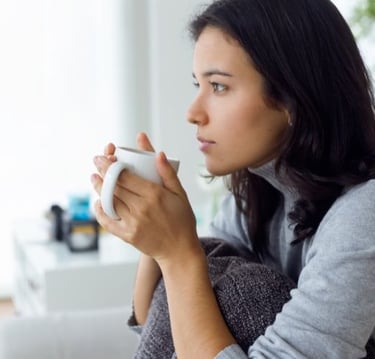 a woman sitting on a couch holding a cup of coffee
