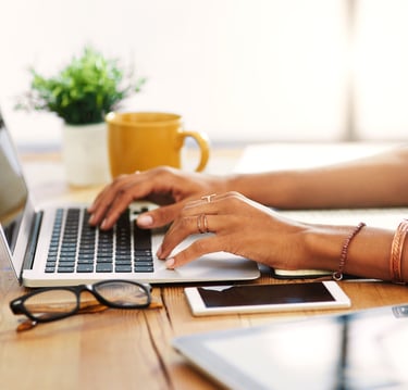 a woman's hands typing on a laptop computer