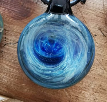 a blue glass pendant necklace with a swirl design