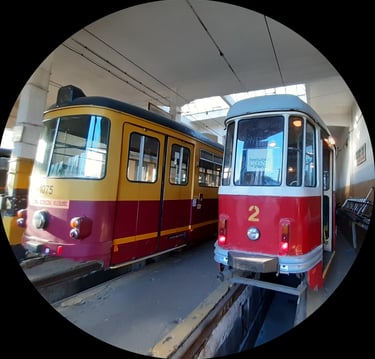 Para zabytkowych tramwajów, żółtoczerwony i białoczerwony, obok siebie, w muzeum.
