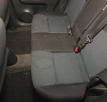 Tylna kanapa samochodu z plamami przed praniem.