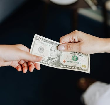 two people holding onto a dollar bill representing gold ira fees and a guide to understanding gold ira fees