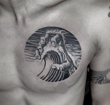 Blackwork tattoo of a hand holding a wave on the chest