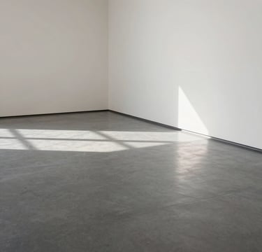 A minimalist, high-angle photograph of an empty gallery space in a North American / US museum. Soft light spills onto a polished grey floor, casting long shadows. The palette is dominated by off-white and charcoal grey, reflecting a contemporary and professional atmosphere.