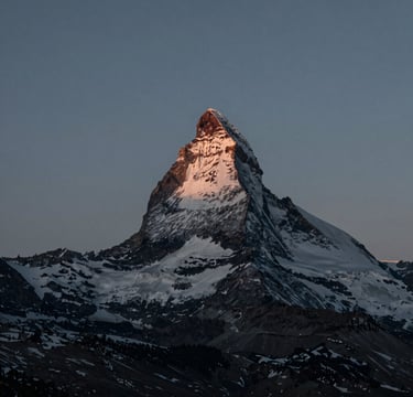 A minimalist landscape photograph of a snow-capped North American mountain peak during the blue hour. The lighting is ethereal and soft. The composition uses a sophisticated palette of dark slate and teal grey, evoking a sense of calm and professional artistry.