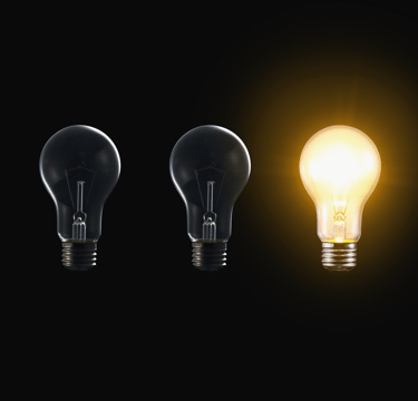 a group of three light bulbs with a glowing yellow light bulb