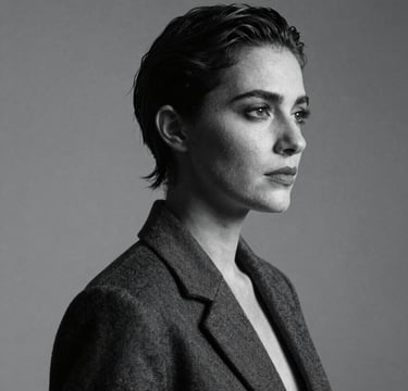 A sophisticated black and white studio portrait of a person with dramatic side lighting, high contrast, slate blue and charcoal tones, elegant and modern Spanish style.