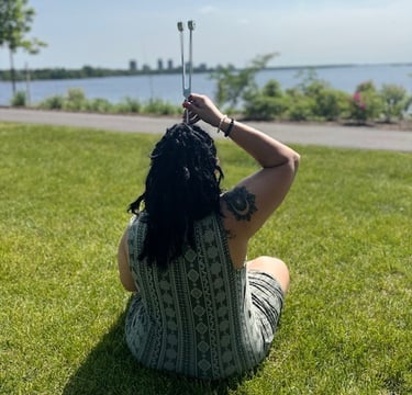 a woman sitting on the grass with a stick in her hand