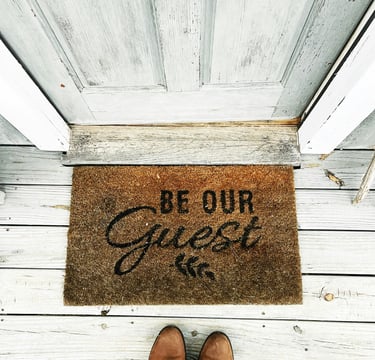 The entrance to the guesthouse with a doormat and the inscription "Be our guest"