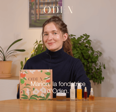 a woman sitting at a table with a box of perfumes