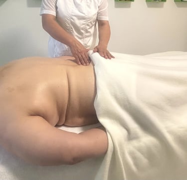 Séance de massage du dos dans une salle de soins, avec une praticienne massant une personne allongée