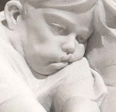 White marble sculpture of a child sitting and playing with a video game console.