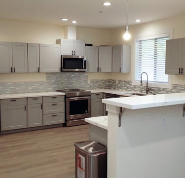 Home-style kitchen in adult family home with stove, refrigerator, and meal preparation space.