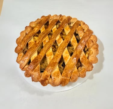 Golden-brown homemade apple pie with a lattice crust and fluted edges on a white background.