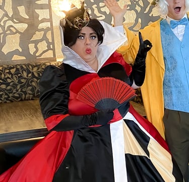 A Queen of Hearts character holding a red fan and wearing a gold crown.