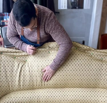 Un artisan couvre d'un tissu jaune à motifs un canapé
