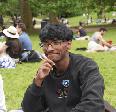 a man in a black shirt and glasses sitting on a blanket qui est adhérent de néoléa