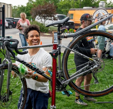 Smiling young man washing a bike with a sponge