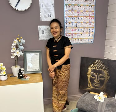 a Thai woman in traditional costume standing in front of a wall with a clock