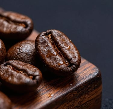 Macro close-up of roasted coffee beans with glistening natural oils adjacent to rich polished teak wood grain, dramatic low-key side lighting, luxury dark navy background.