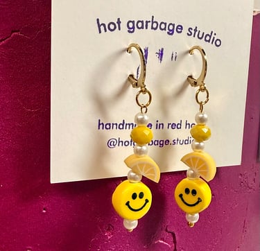 Gold huggie-hoop dangle earrings with yellow smiley faces and beads
