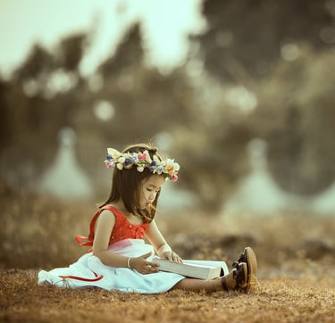 little girl reading a boog outside