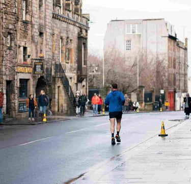 Man jogging on wet urban street with historic stone buildings in background