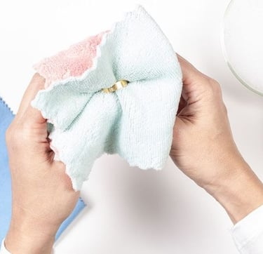 Manos utilizando un paño de microfibra suave para limpiar y pulir joyería