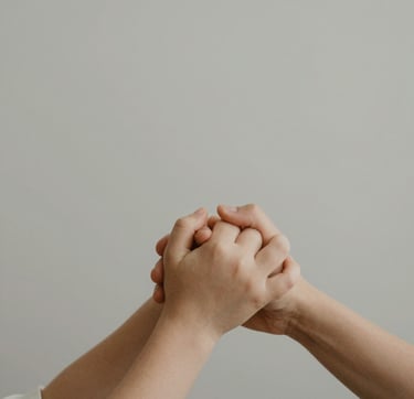 A minimalist lifestyle detail shot of a family's hands joined together, captured in soft natural light. The scene features earthy textures and a palette of #C8B6A6 and #7B6654, evoking a sense of authentic storytelling and timeless warmth.