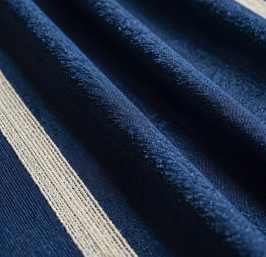 A cinematic, editorial-style close-up of experimental textile textures featuring deep indigo blue and ivory threads, softly lit in a dark studio. The composition captures the intricate weave of silk and hemp. The scene reflects a East Asian / South Asian influenced for a global luxury audience aesthetic with soft shadows and refined highlights.