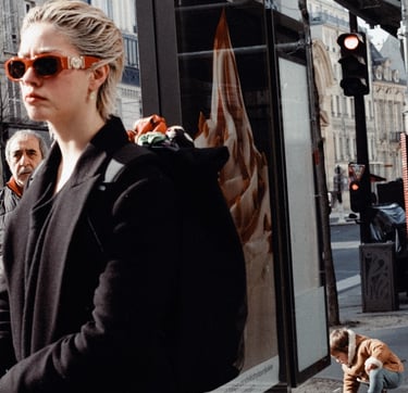 a woman in a black coat and sunglasses on a city street