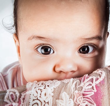 a baby girl with a pink blanket on her lap