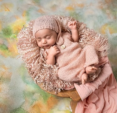 a baby girl sleeping in a basket with a pink blanket